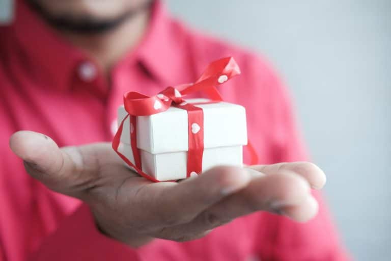 Man holding a white Christmas gift box with a red ribbon