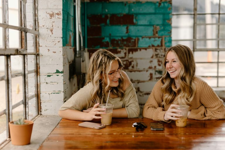 Two women friends talking over drinks at a table