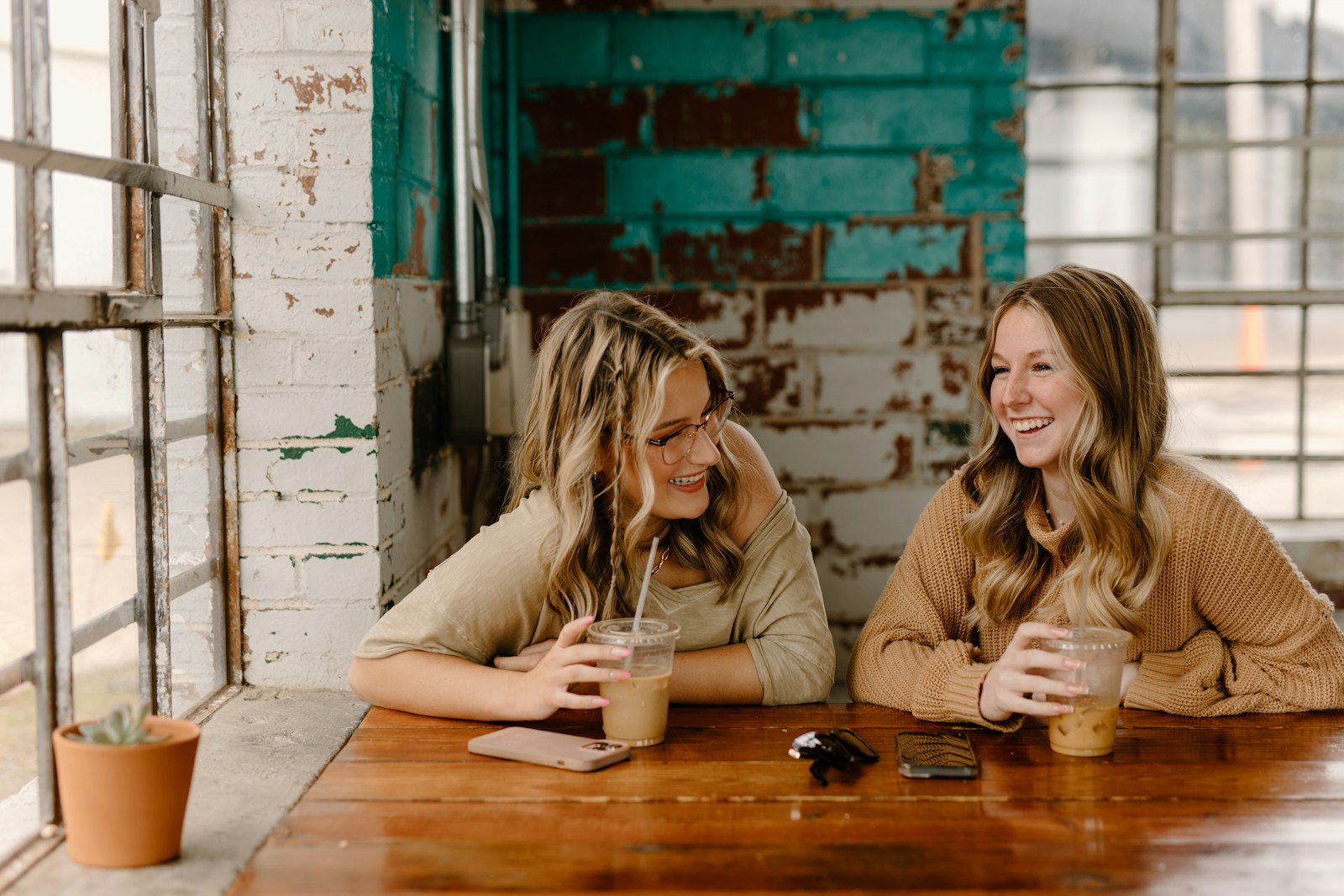 Two women friends talking over drinks at a table
