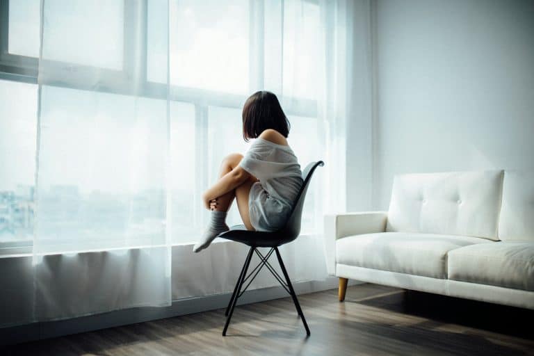 Woman sitting alone looking out a window