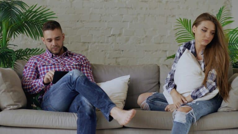 Couple sitting apart on a sofa, looking away from each other