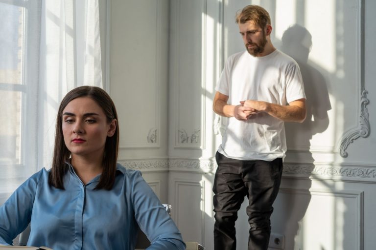 Couple sitting apart on a couch with tension between them