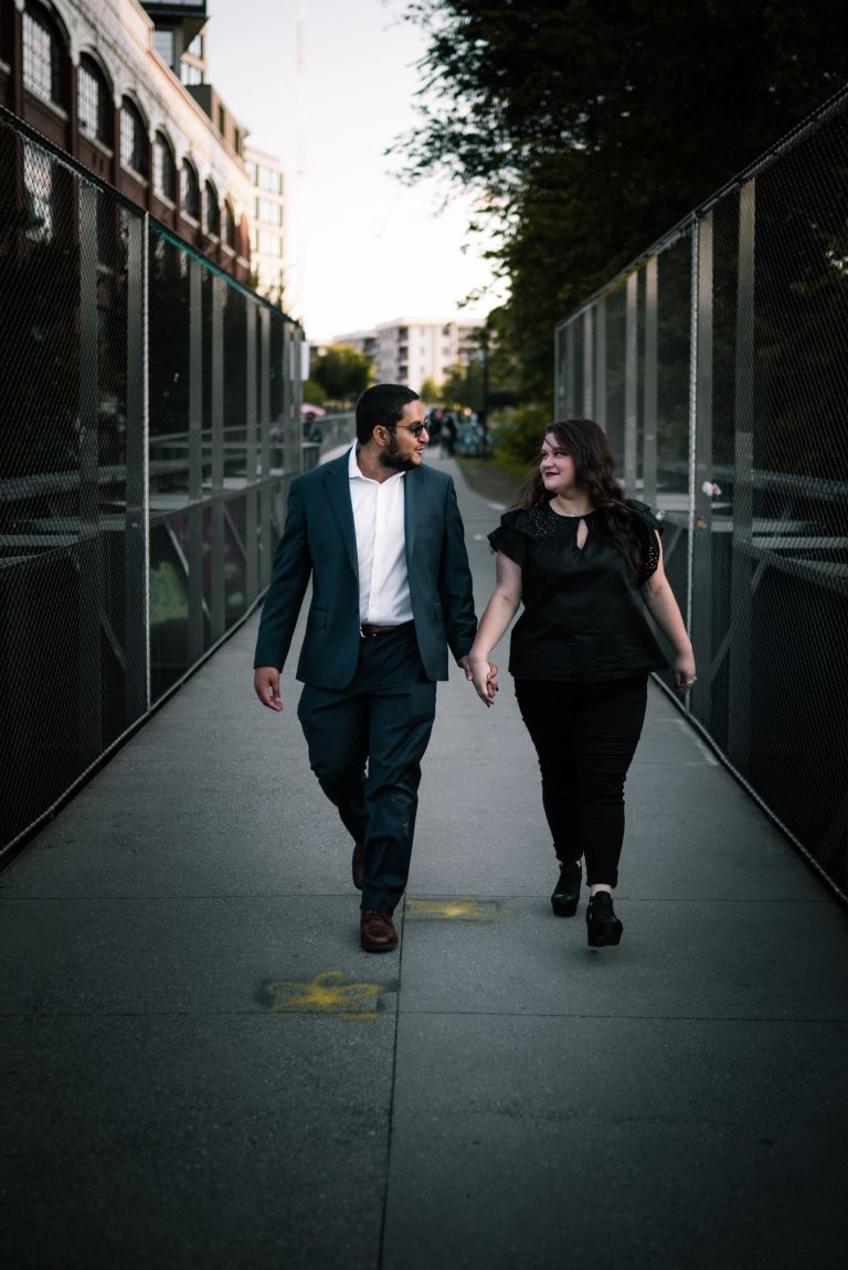 Man and woman holding hands and looking at each other while crossing a city street