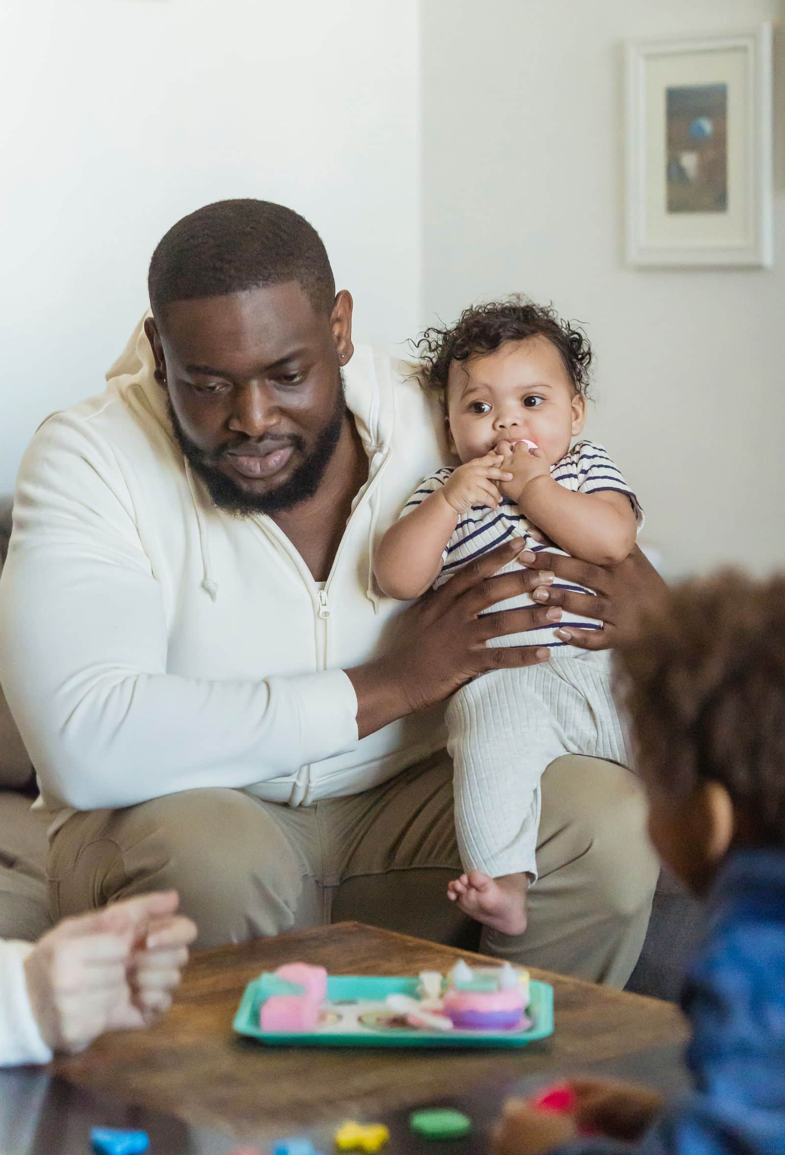 Father holding his baby while playing with his children at home
