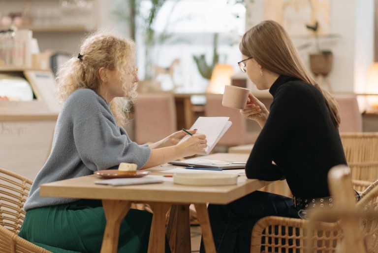 Two women friends talking over coffee in a cozy cafe