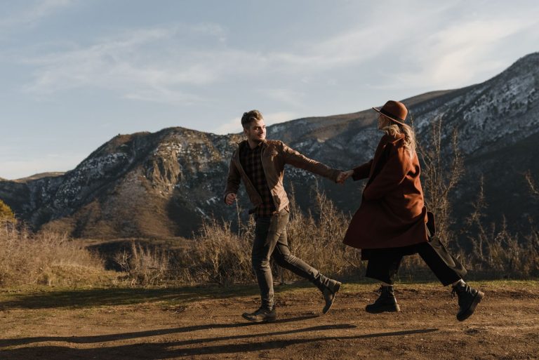 Young married couple joyfully running hand in hand in the mountains